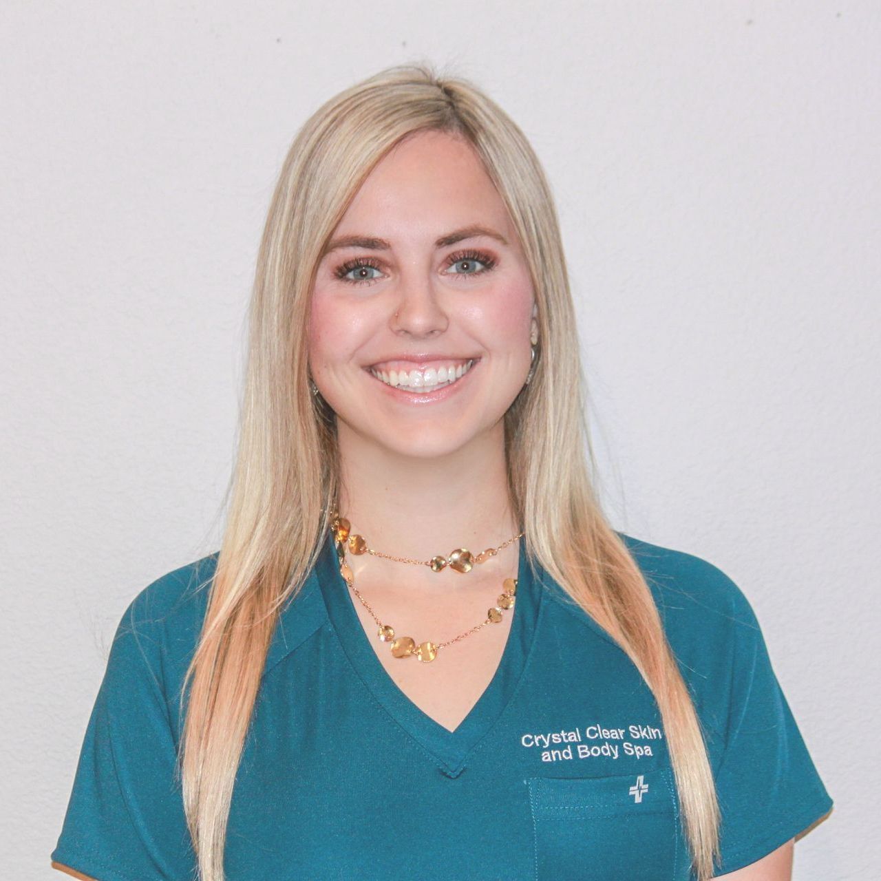 Smiling woman in teal scrubs against a light gray background